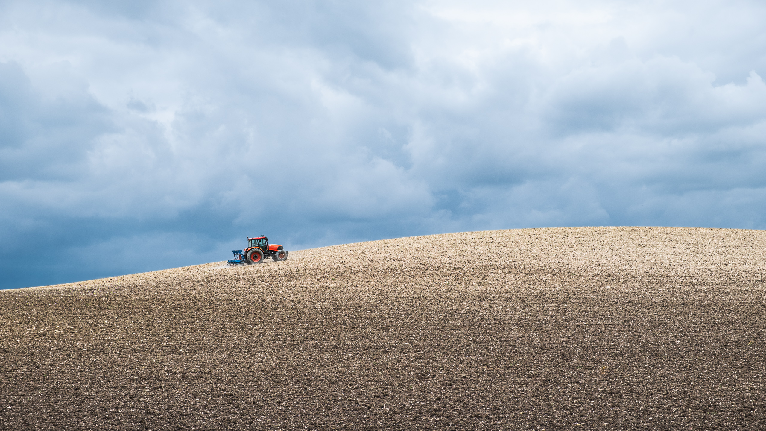 Roter Traktor am Horizont eines frisch gepflügten Feldes